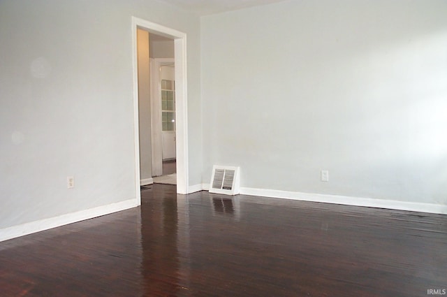 spare room featuring wood finished floors, visible vents, and baseboards