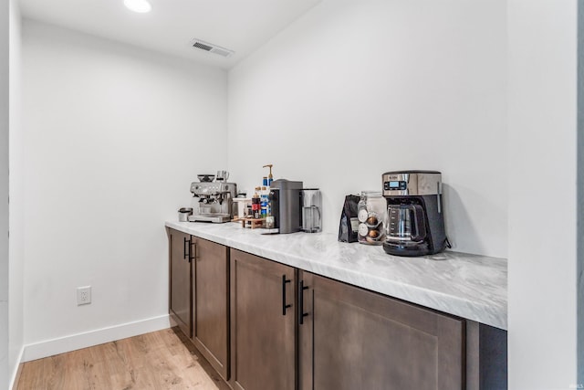 bar featuring light wood-style floors, visible vents, and baseboards