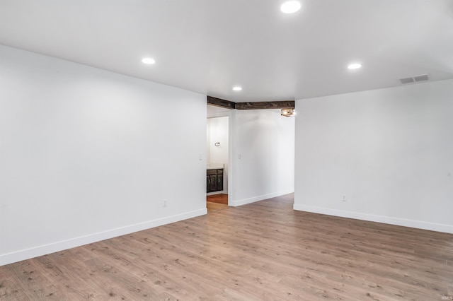 empty room featuring light wood-type flooring, visible vents, baseboards, and recessed lighting