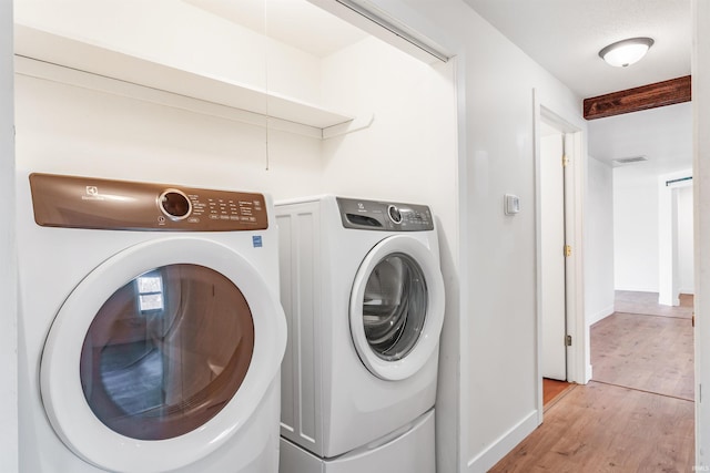 laundry room with laundry area, light wood-type flooring, independent washer and dryer, and baseboards