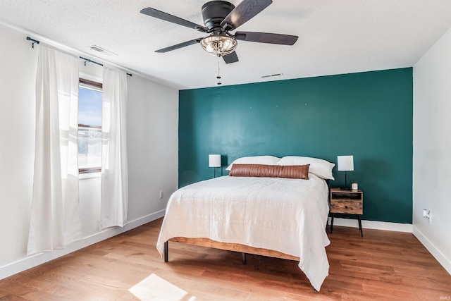 bedroom featuring wood finished floors, visible vents, and baseboards