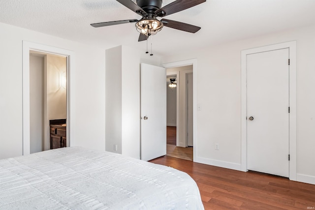 bedroom featuring ceiling fan, a textured ceiling, baseboards, and wood finished floors