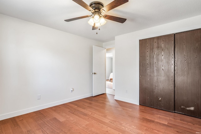 unfurnished bedroom featuring ceiling fan, a closet, wood finished floors, and baseboards