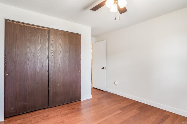 unfurnished bedroom with a closet, ceiling fan, baseboards, and wood finished floors