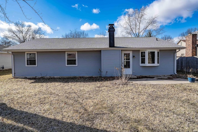 back of property featuring a shingled roof, fence, a yard, a chimney, and a patio area