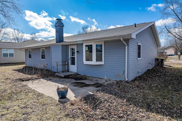 back of house featuring a shingled roof, a chimney, and a patio area