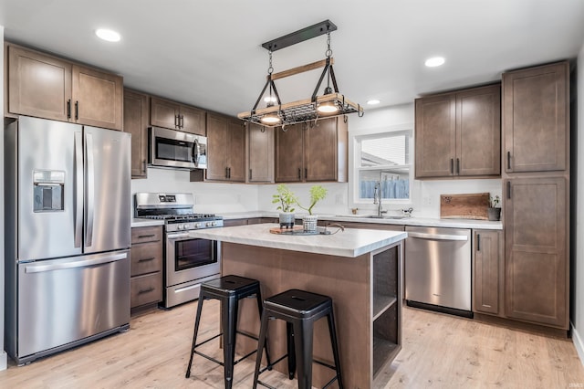 kitchen with light wood-type flooring, stainless steel appliances, a sink, and light countertops