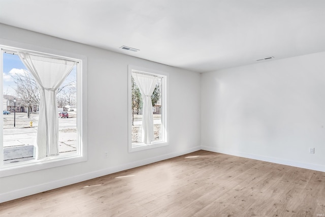 empty room featuring baseboards, visible vents, and light wood-style floors