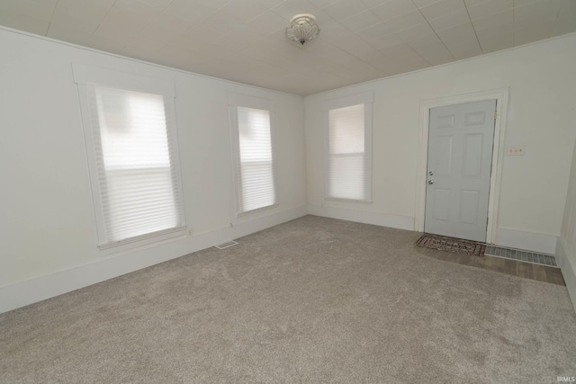 carpeted empty room featuring baseboards and visible vents