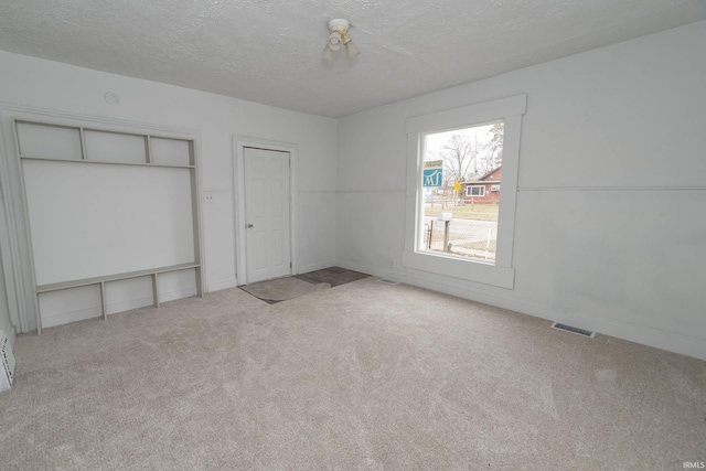 unfurnished bedroom with a textured ceiling, carpet flooring, and visible vents