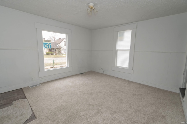 spare room featuring a textured ceiling, carpet, and visible vents