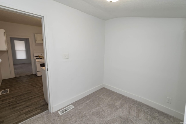 empty room featuring dark carpet, visible vents, and baseboards