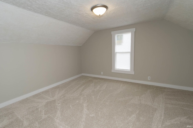 bonus room featuring lofted ceiling, baseboards, a textured ceiling, and light colored carpet