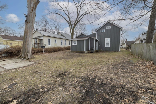 rear view of house featuring metal roof, a storage shed, an outdoor structure, fence, and board and batten siding