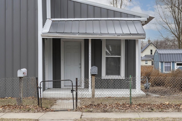 doorway to property featuring a gate, fence, and metal roof