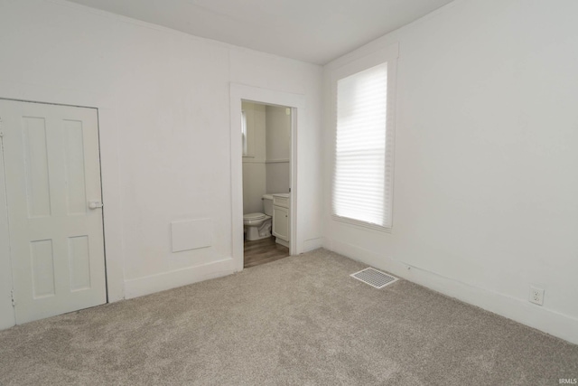 unfurnished bedroom featuring carpet, connected bathroom, and visible vents