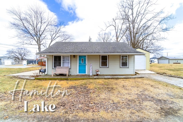 view of front of house with a garage, a shingled roof, dirt driveway, covered porch, and a front lawn