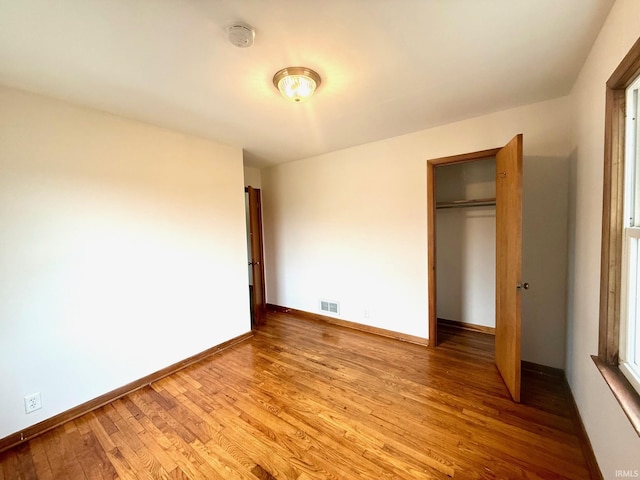 unfurnished bedroom with a closet, baseboards, visible vents, and light wood finished floors