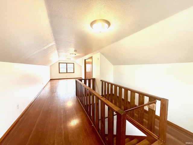 bonus room with a textured ceiling, hardwood / wood-style floors, vaulted ceiling, and baseboards