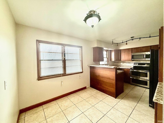 kitchen featuring stainless steel appliances, light countertops, a peninsula, and light tile patterned flooring