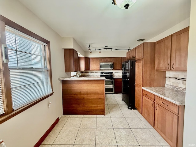 kitchen with light tile patterned floors, stainless steel appliances, baseboards, brown cabinets, and tasteful backsplash