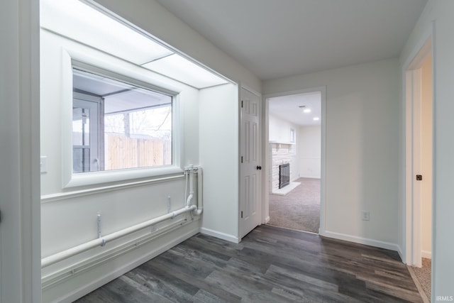 hall featuring dark wood-style flooring and baseboards