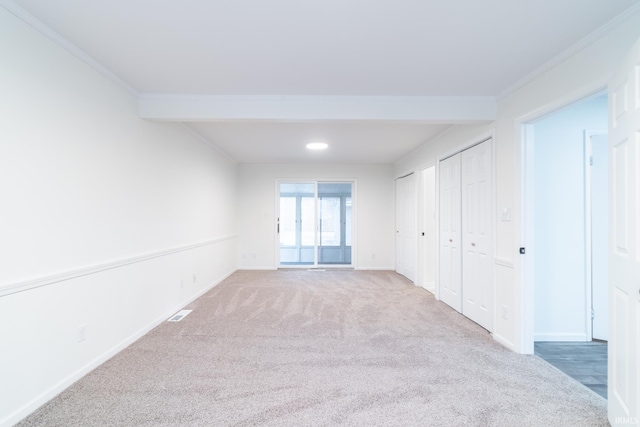 carpeted empty room featuring visible vents, baseboards, and crown molding