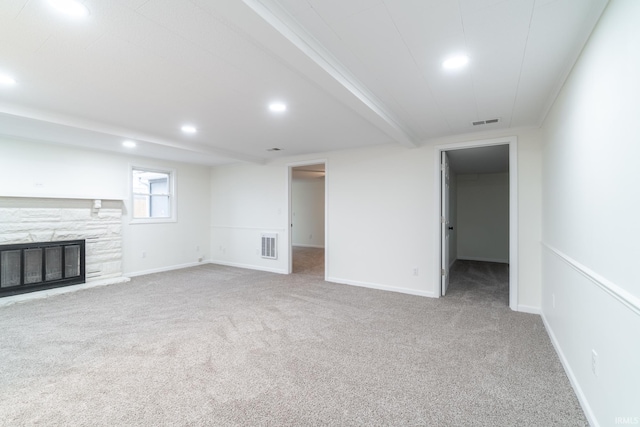 unfurnished living room featuring carpet, visible vents, and a stone fireplace