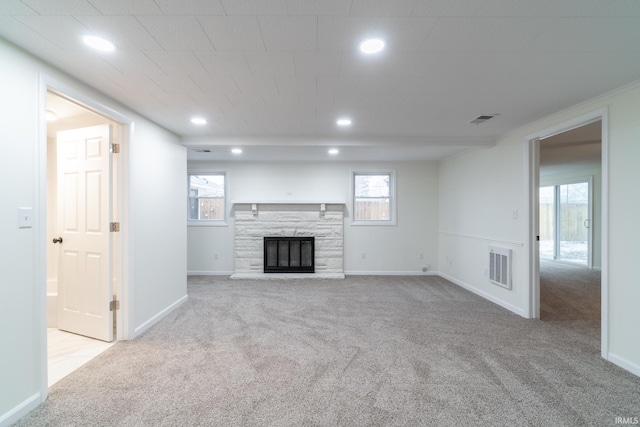 unfurnished living room with a fireplace, carpet flooring, and visible vents