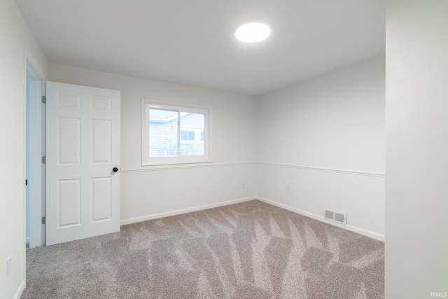 carpeted spare room with visible vents and baseboards