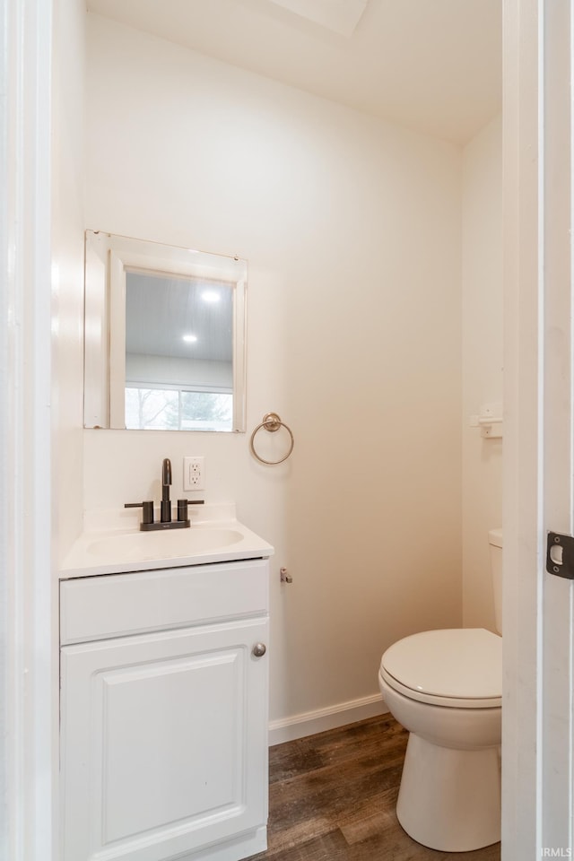 bathroom with baseboards, vanity, toilet, and wood finished floors