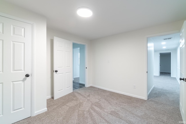 unfurnished bedroom with carpet, visible vents, and baseboards