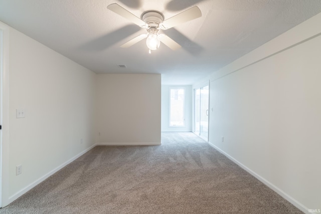 carpeted empty room with ceiling fan, a textured ceiling, visible vents, and baseboards