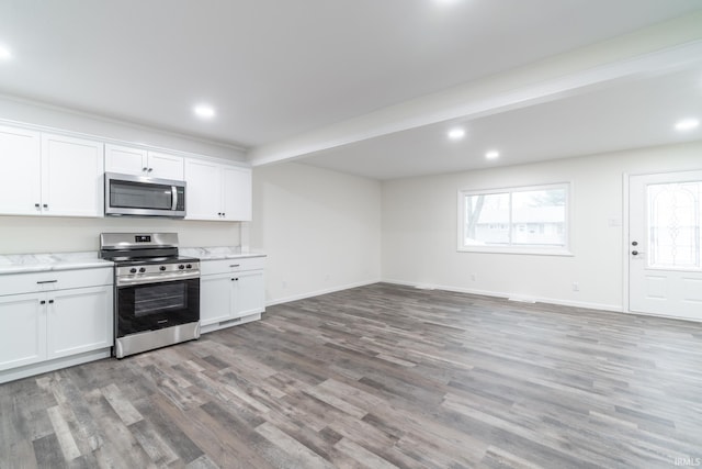 kitchen featuring baseboards, open floor plan, white cabinets, appliances with stainless steel finishes, and light wood-type flooring