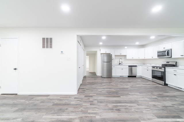 kitchen with visible vents, stainless steel appliances, light countertops, light wood-type flooring, and white cabinetry