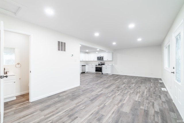 unfurnished living room featuring recessed lighting, visible vents, light wood-style floors, a healthy amount of sunlight, and baseboards