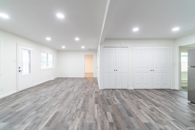 basement with baseboards, wood finished floors, freestanding refrigerator, and recessed lighting