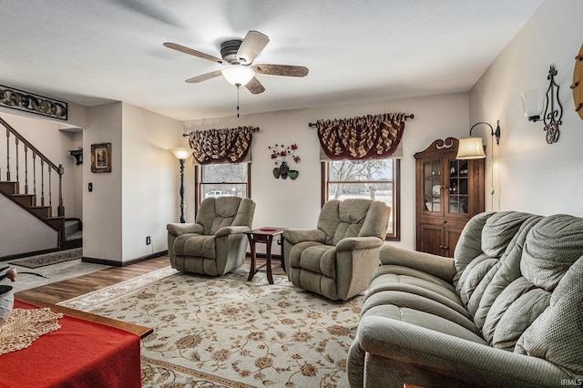 living room featuring stairs, ceiling fan, wood finished floors, and baseboards