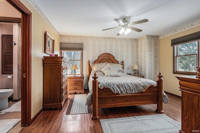 bedroom featuring baseboards, ceiling fan, wood finished floors, and wallpapered walls