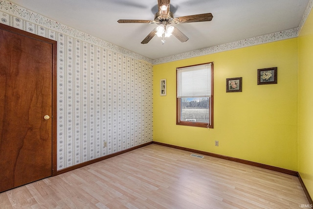 spare room featuring baseboards, light wood finished floors, visible vents, and wallpapered walls