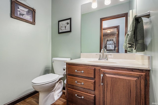 bathroom with baseboards, vanity, toilet, and wood finished floors