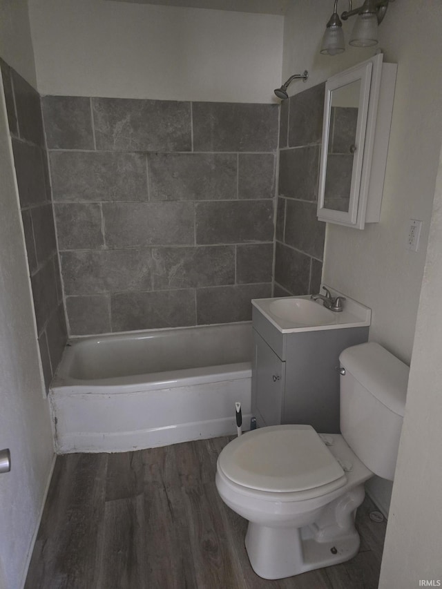 bathroom with vanity, toilet, wood finished floors, and washtub / shower combination