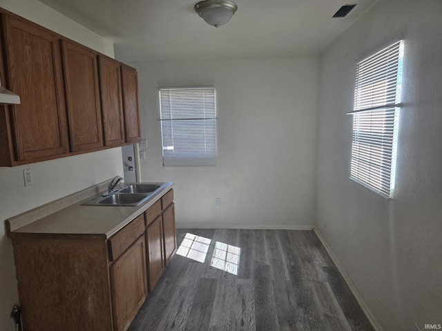 kitchen with visible vents, a sink, dark wood finished floors, light countertops, and baseboards