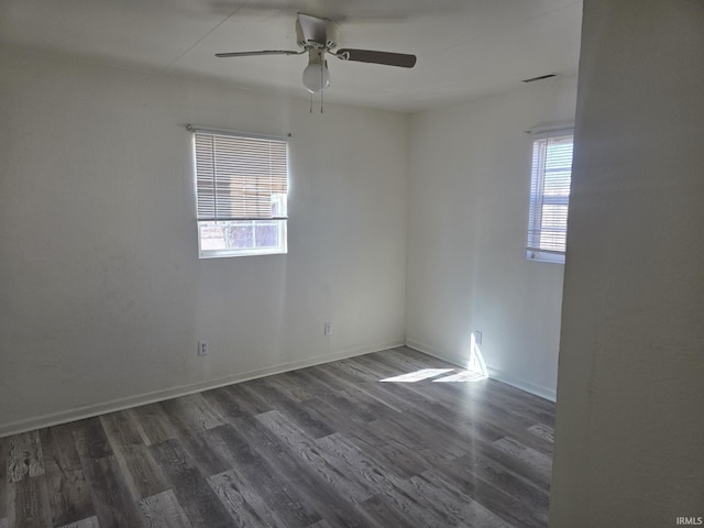 spare room with a wealth of natural light, visible vents, baseboards, and wood finished floors