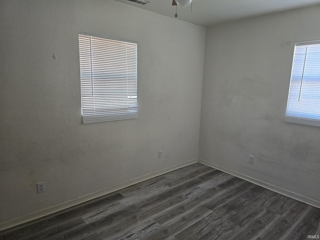 unfurnished room featuring ceiling fan, visible vents, baseboards, and dark wood-style floors