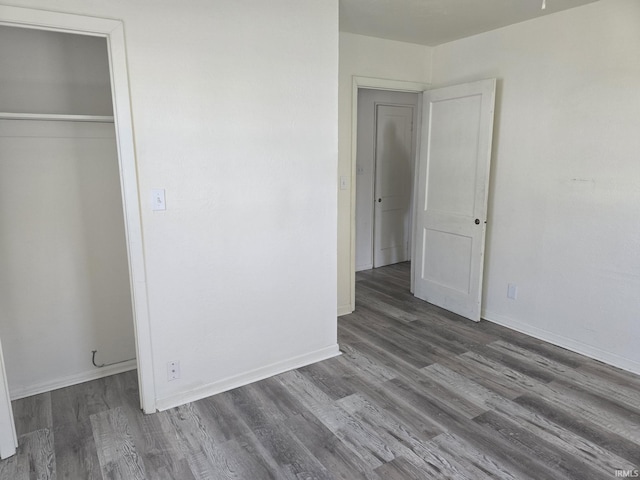 unfurnished bedroom with a closet, baseboards, and wood finished floors