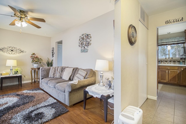 living room with ceiling fan, visible vents, and baseboards