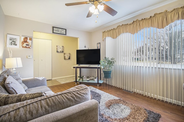 living area with a ceiling fan, baseboards, and wood finished floors