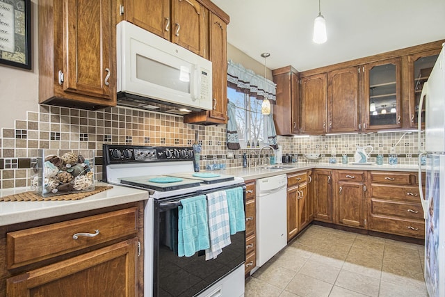 kitchen featuring light tile patterned flooring, white appliances, a sink, light countertops, and tasteful backsplash