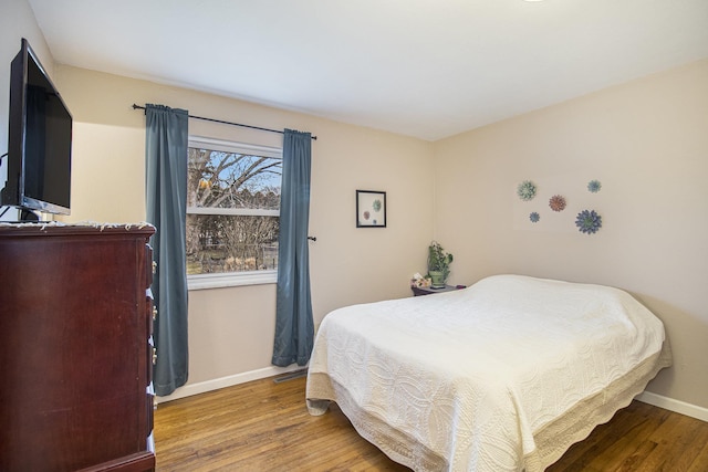 bedroom with wood finished floors, visible vents, and baseboards